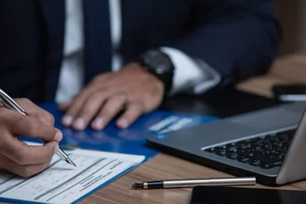 Business professional reviewing documents at desk with laptop.