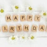 Wooden blocks spelling Happy Birthday surrounded by daisies.
