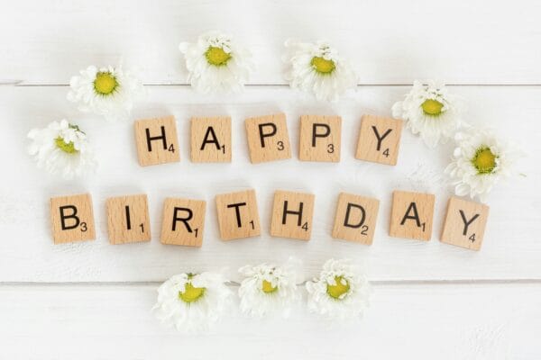 Wooden blocks spelling Happy Birthday surrounded by daisies.