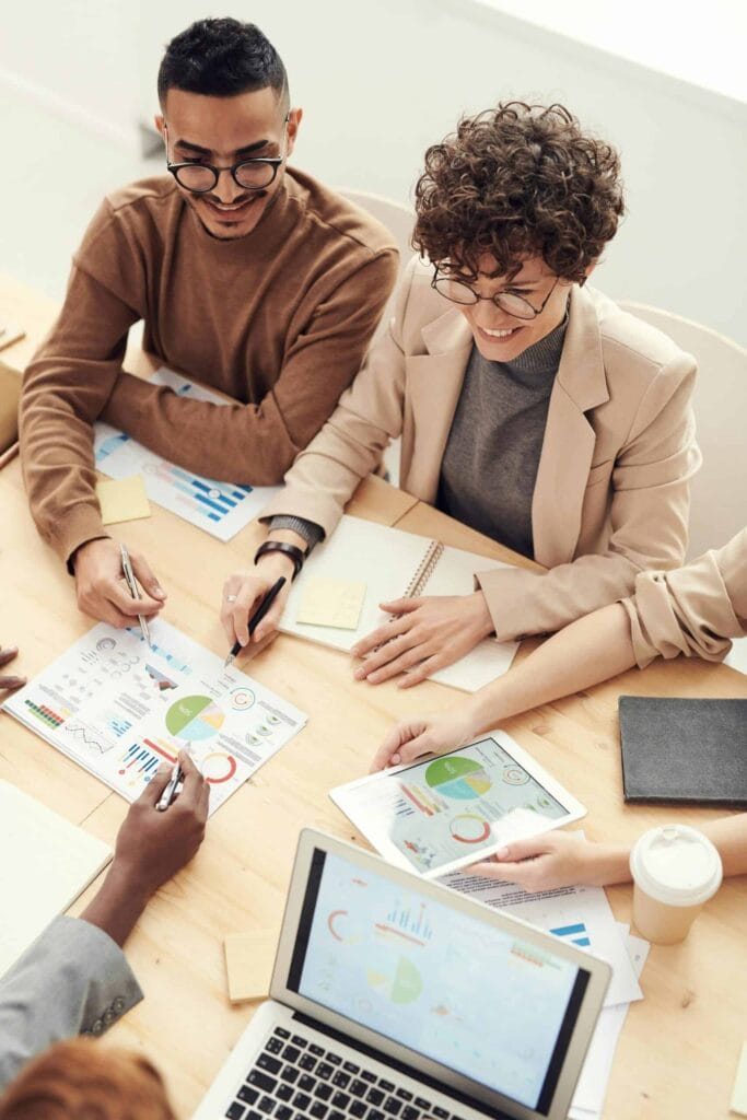 A team of colleagues collaboratively reviewing printed and digital data charts during a risk analysis meeting.