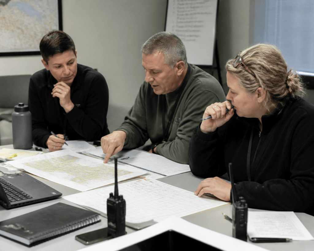 Team coordinating around a map with handheld radios during an incident response